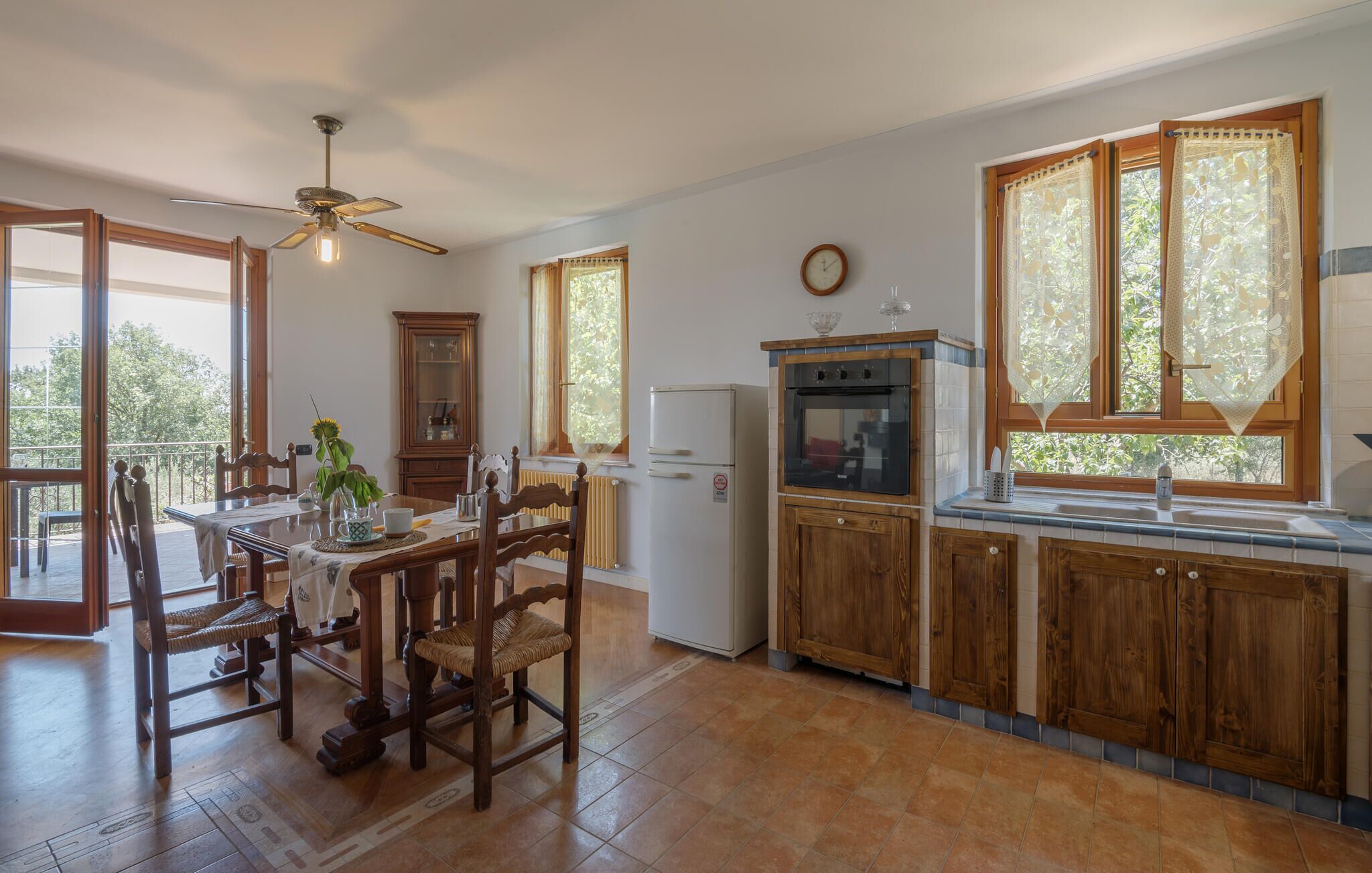 A kitchen with wooden cabinets, a refrigerator, a stove, and a dining area with a table and chairs.