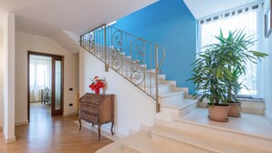 Un escalier orné de rampes en métal ouvragé, une commode en bois et une plante en pot.