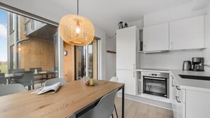 Una cocina moderna con armarios blancos, horno empotrado y cafetera.