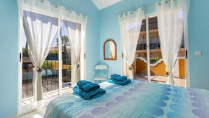 A bedroom with a bed, two windows with curtains, a chair, and a view of a balcony. - Cozy home in Mazarrón (Mazarrón)