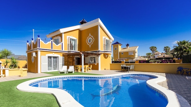 A yellow villa with a swimming pool, a patio with chairs, and a view of the surrounding area. - Cozy home in Mazarrón (Mazarrón)