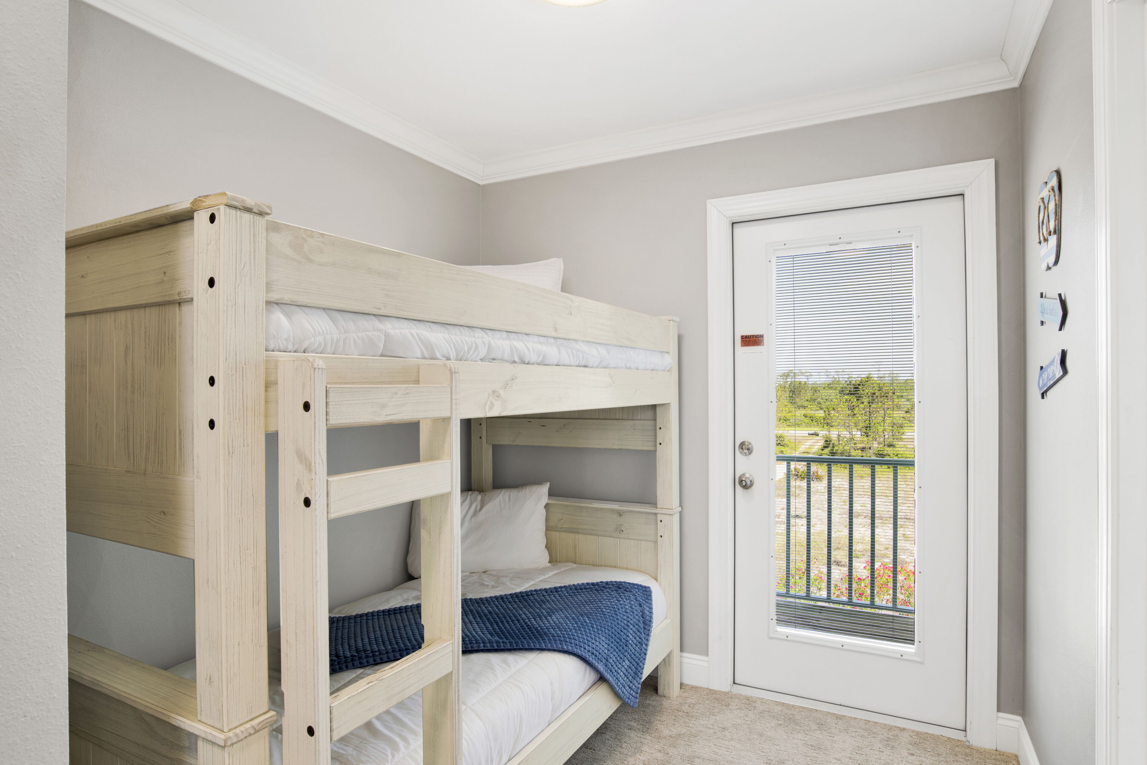 A bunk bed room with a door leading to an outdoor balcony.