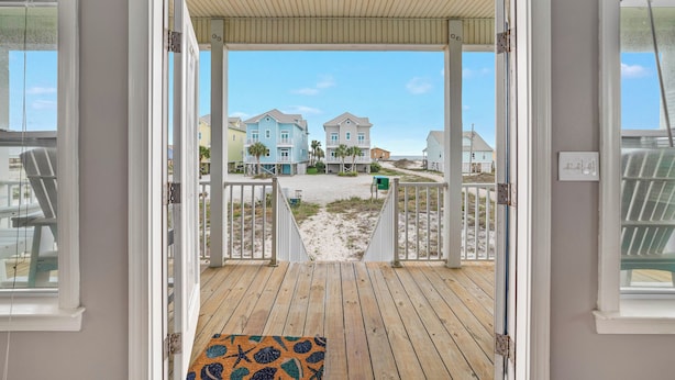 A wooden deck with a view of beach houses and a sandy path.