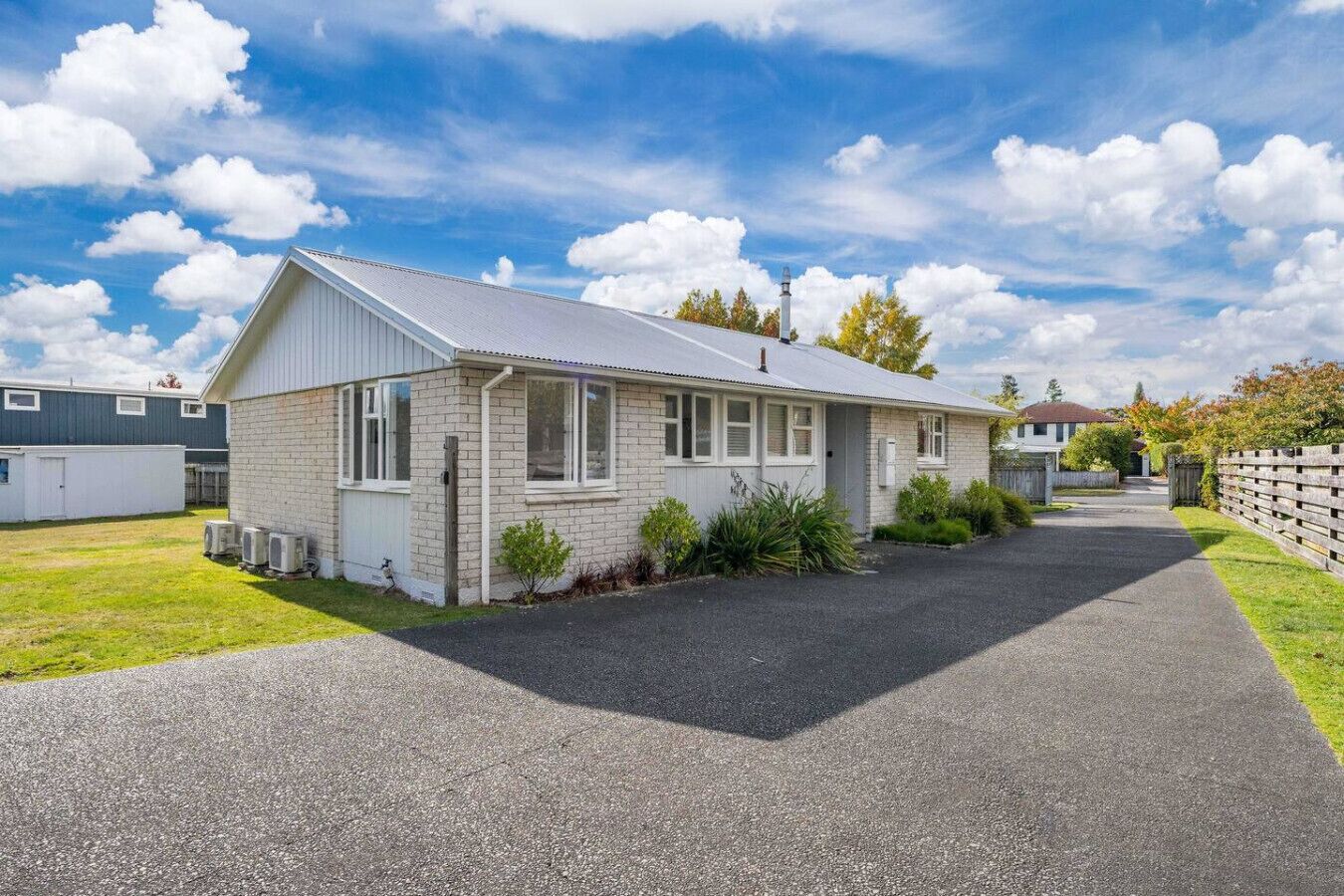 A single-story house with a sloped roof, a front porch, and a paved driveway.