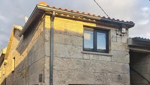 A stone building with a tiled roof, a window, and a door. - Casa da Capela (Ponte da barca)