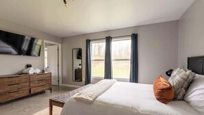 Ein Schlafzimmer mit einem Bett, einem Schminktisch, einem Fernseher und einem Fenster.