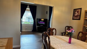 A living room with a dining table, chairs, a TV, and a vase with flowers. - Harold Hidden Haven - Close to area Hospitals (Johnstown)