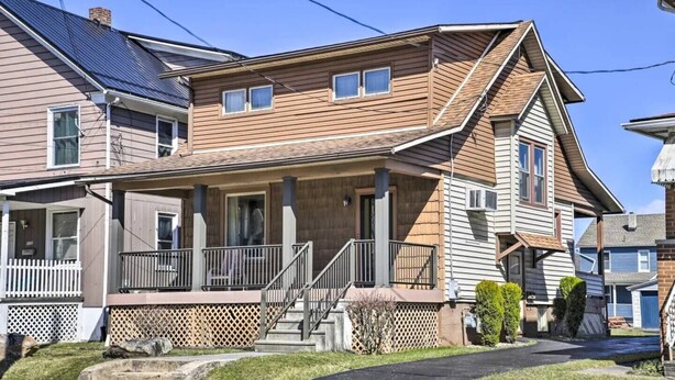 Une maison à deux étages avec un porche à l’avant, un hall d’entrée couvert et un petit jardin devant la maison.
