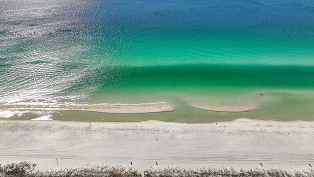 A beach with clear turquoise waters and a sandy shore.