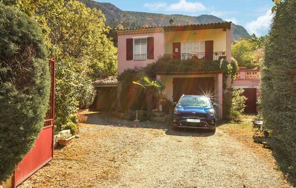 Uma casa de dois andares com um carro estacionado na entrada.