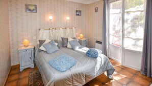 Un dormitorio con una cama, dos mesitas de noche, una lámpara y una ventana con cortinas.