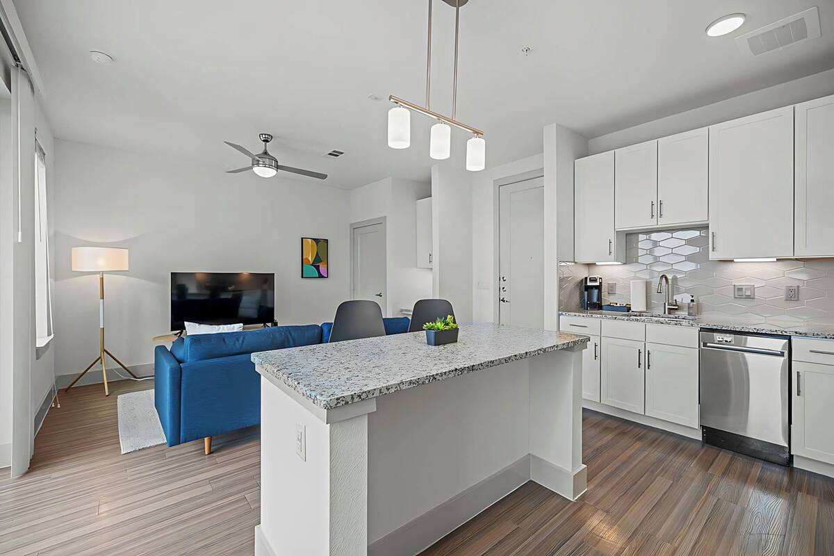 A modern kitchen with white cabinets, a granite countertop, and stainless steel appliances.