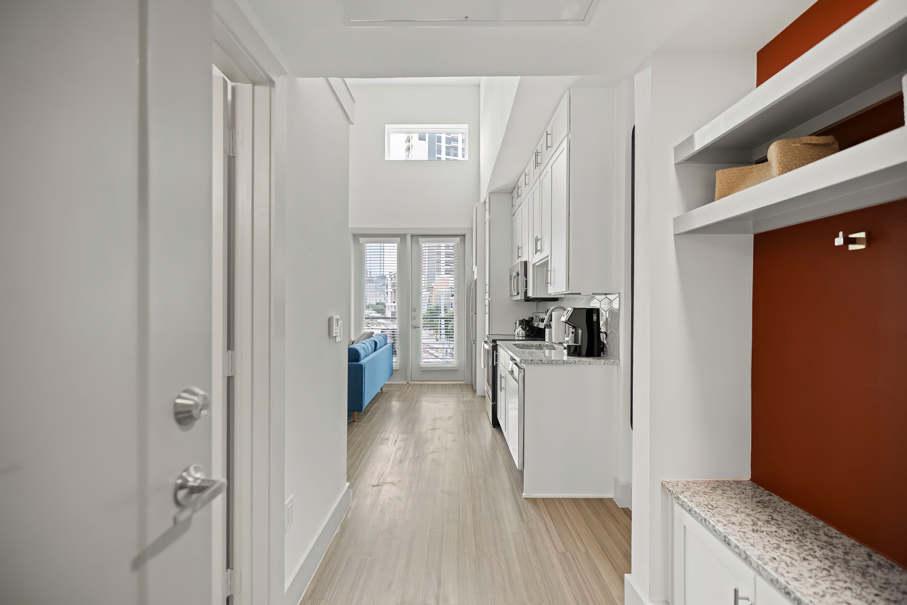 Una cocina moderna con muebles blancos, encimera de granito y vistas al área de estar.