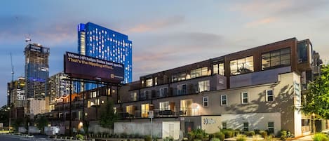 Un edificio moderno con varios pisos, grandes ventanales y un cartel llamativo.