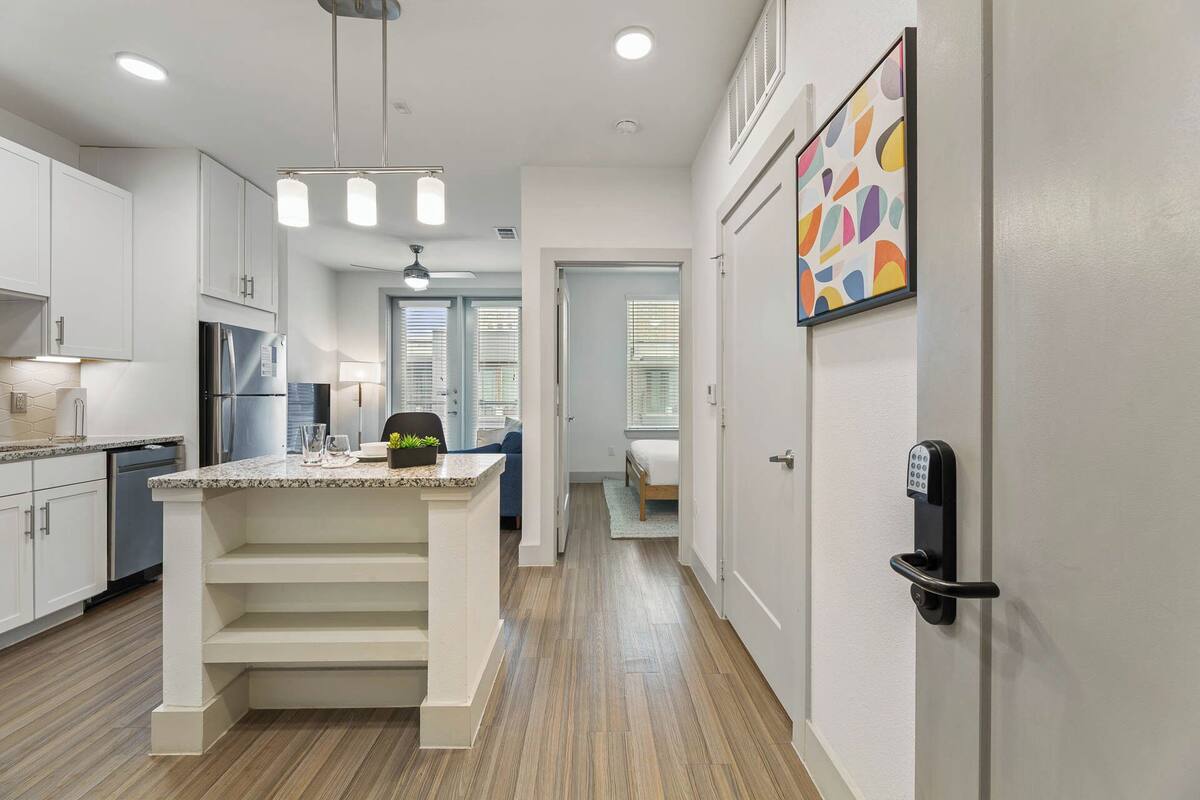 A modern kitchen with white cabinetry, a granite countertop, and a stainless steel refrigerator.