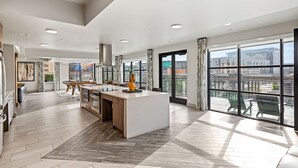 A modern kitchen with a central island, large windows, and a view of the city. - Placemakr Austin Downtown, Apartments by Hilton (Austin)