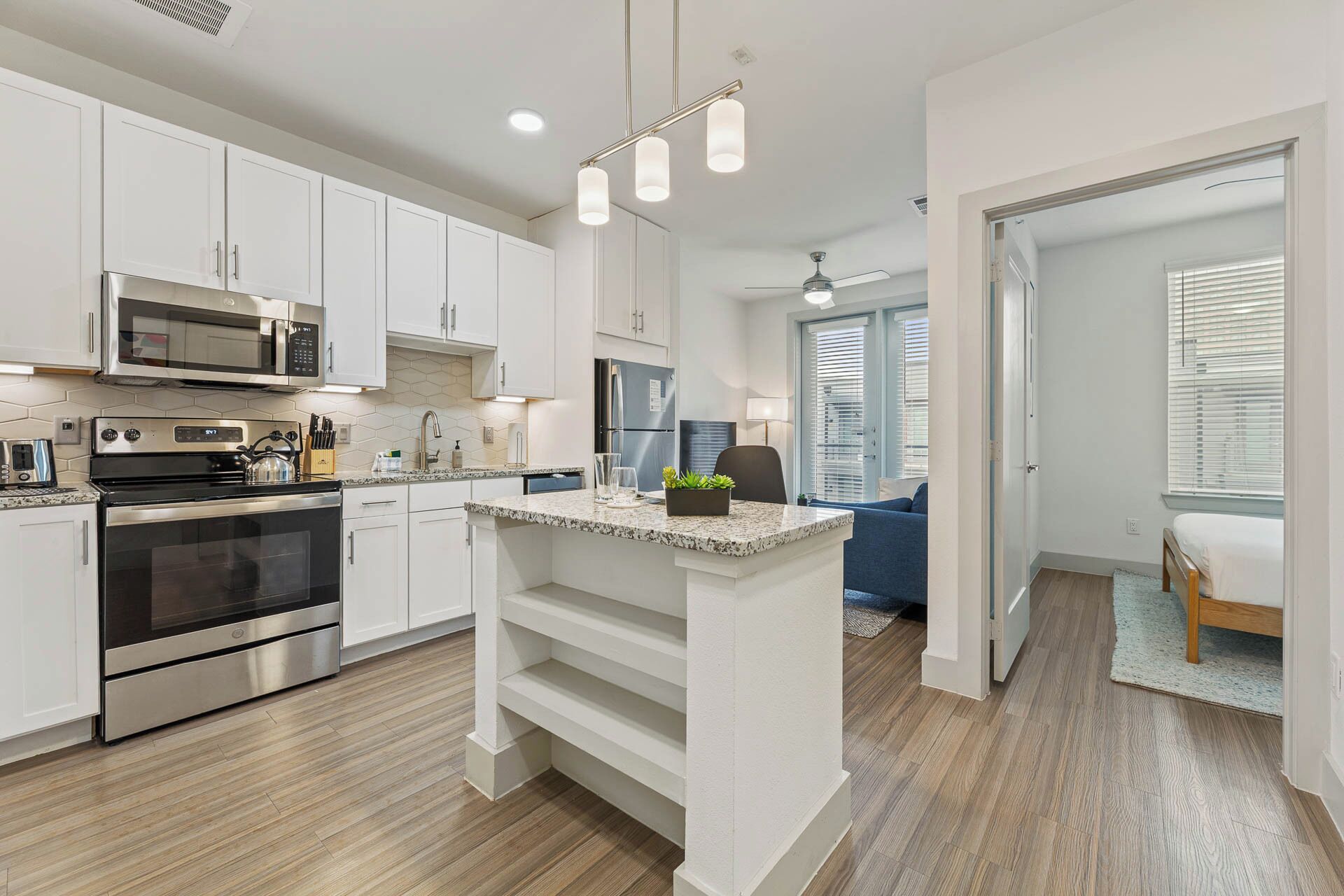 A modern kitchen with white cabinets, stainless steel appliances, and a central island.