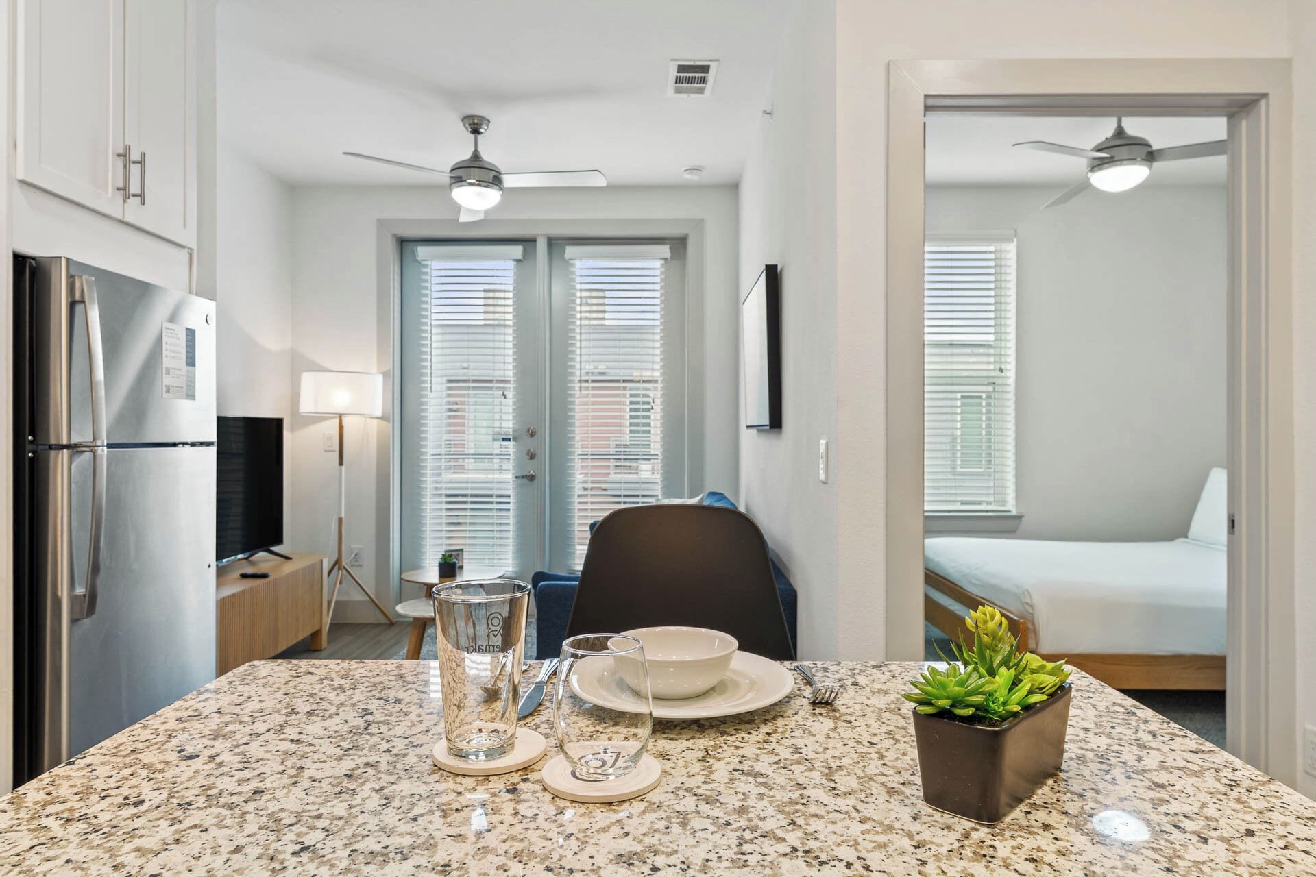 A compact kitchen with a refrigerator, a dining table with a plant, and a chair.