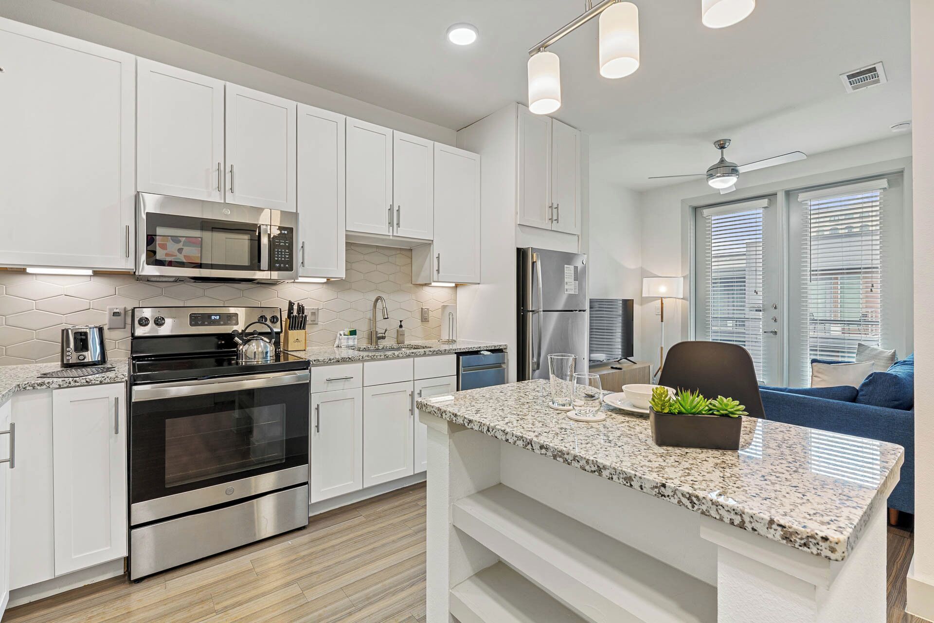 A modern kitchen with white cabinets, stainless steel appliances, and a granite countertop.