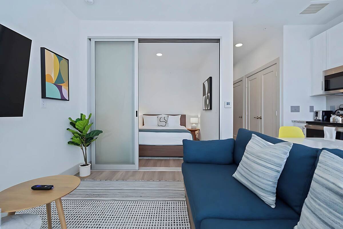 A modern, compact living space with a sofa, a small table, and a potted plant.