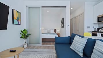 A modern, compact living space with a sofa, a small table, and a potted plant.