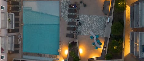 An aerial view of a courtyard with a swimming pool, seating areas, and surrounding buildings.