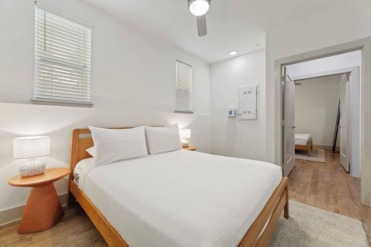 A modern bedroom with a large bed, bedside lamps, and a ceiling light.