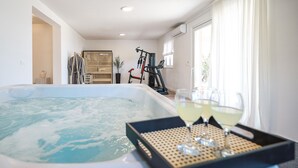 A modern living room with a hot tub, exercise equipment, and a glass of wine on a tray. - Beach front home in Maslenica with sauna (Maslenica)