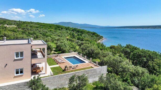 A modern building with a rooftop pool, surrounded by lush greenery and a view of the sea. - Beach front home in Maslenica with sauna (Maslenica)