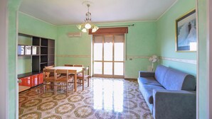 Un comedor con mesa y sillas, un sofá, un ventilador de techo y una ventana con vistas.