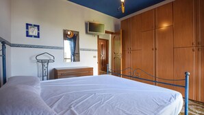 Un dormitorio con cama, armario de madera, televisor y espejo.