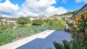 Un pueblo costero con una iglesia destacada, casas escalonadas y una barandilla metálica verde que da al mar.
