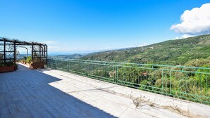 Terraza con baranda de metal que da a un paisaje montañoso.