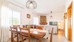 Un coin repas avec une table et des chaises en bois, une cheminée en pierre, un téléviseur et un lampadaire.