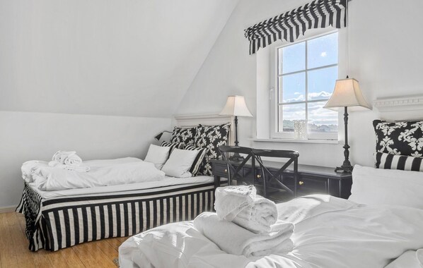 A bedroom with two beds, a window with a view, and a nightstand with a lamp.