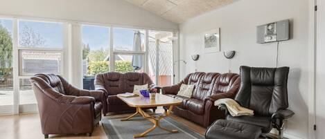 A spacious living room with leather sofas, a coffee table, and a black chair.