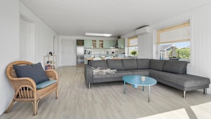 A modern living room with a grey sectional sofa, a blue coffee table, and a wicker chair. - Nice home in Hesselager with WiFi (Hesselager)