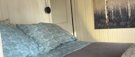 Un dormitorio con cama, una puerta y una pared con estampado floral.