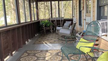 A covered porch with patterned flooring, metal chairs, and a table.