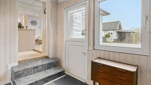 A hallway with a wooden interior, a door leading outside, and a view of a house through a window. - Beautiful home in Otterup with WiFi (Otterup)