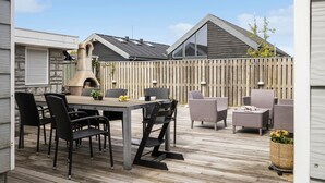 A patio area with a table and chairs, a pizza oven, and a wooden fence. - Beautiful home in Otterup with WiFi (Otterup)