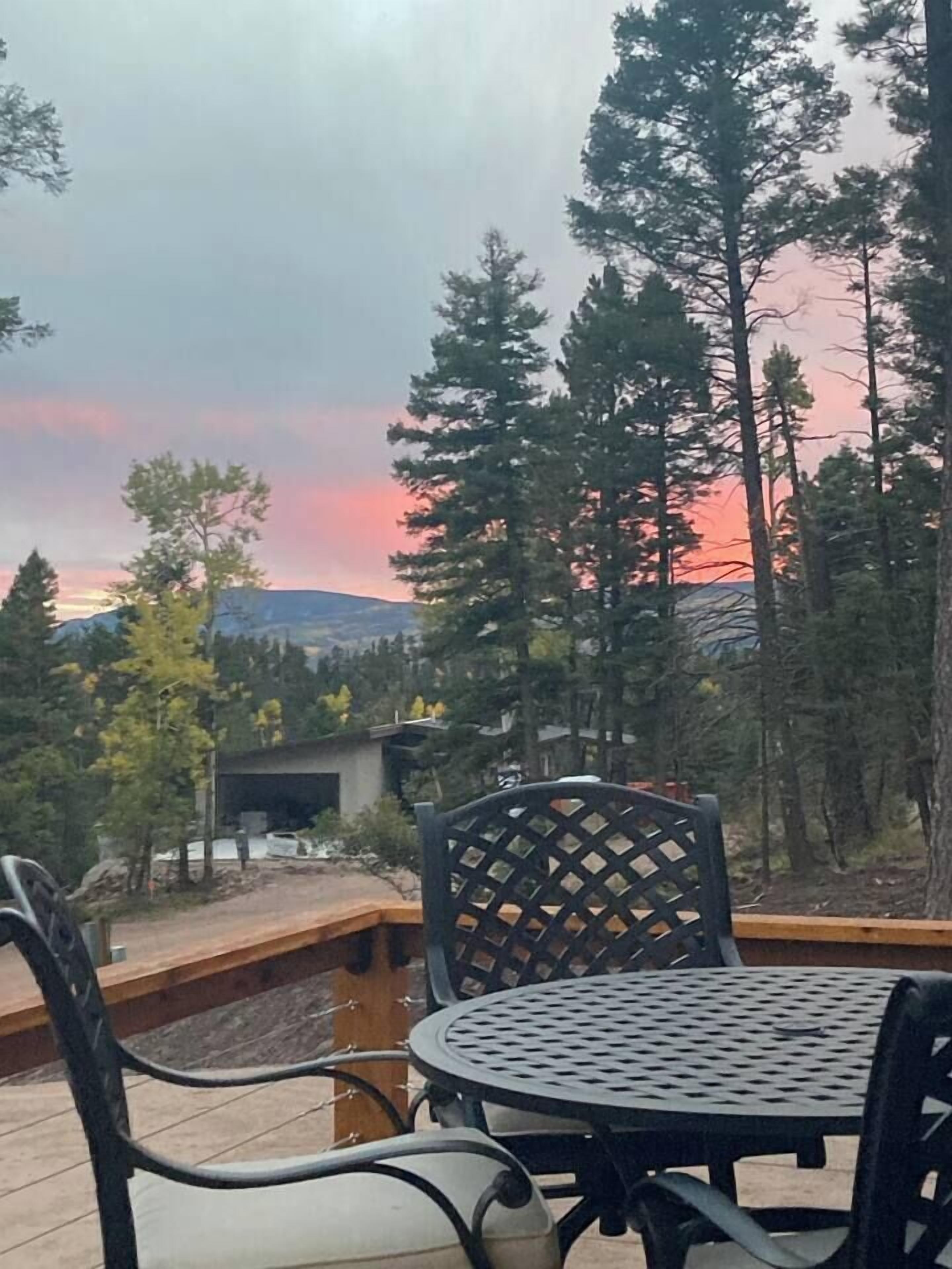 A deck with outdoor seating and a view of a forest and mountains.