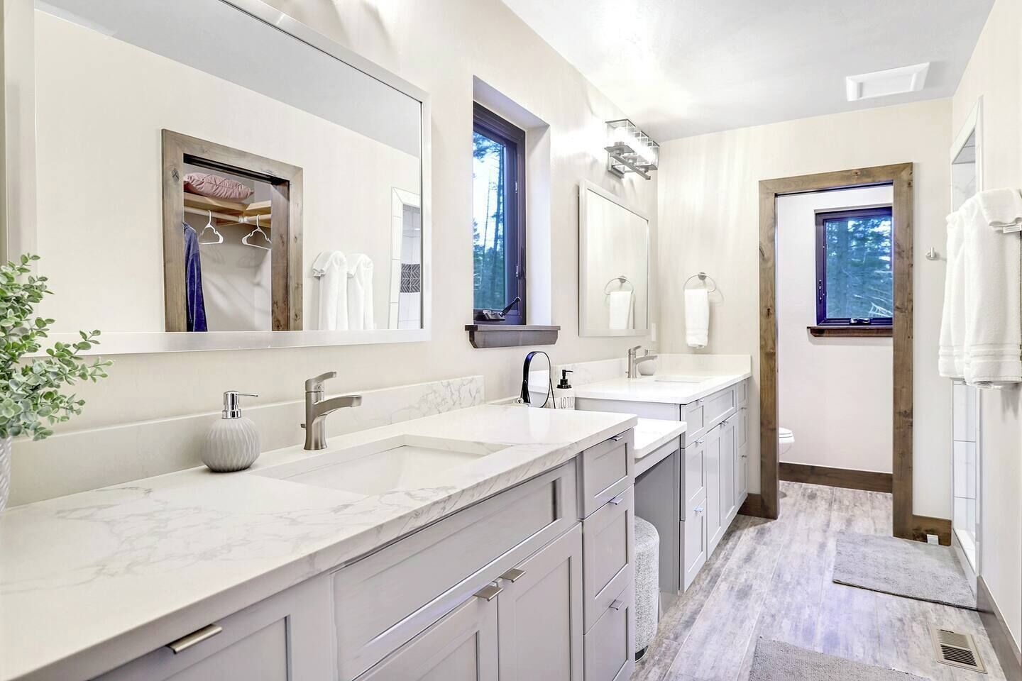 A modern bathroom with two sinks, large mirrors, and a walk-in shower.