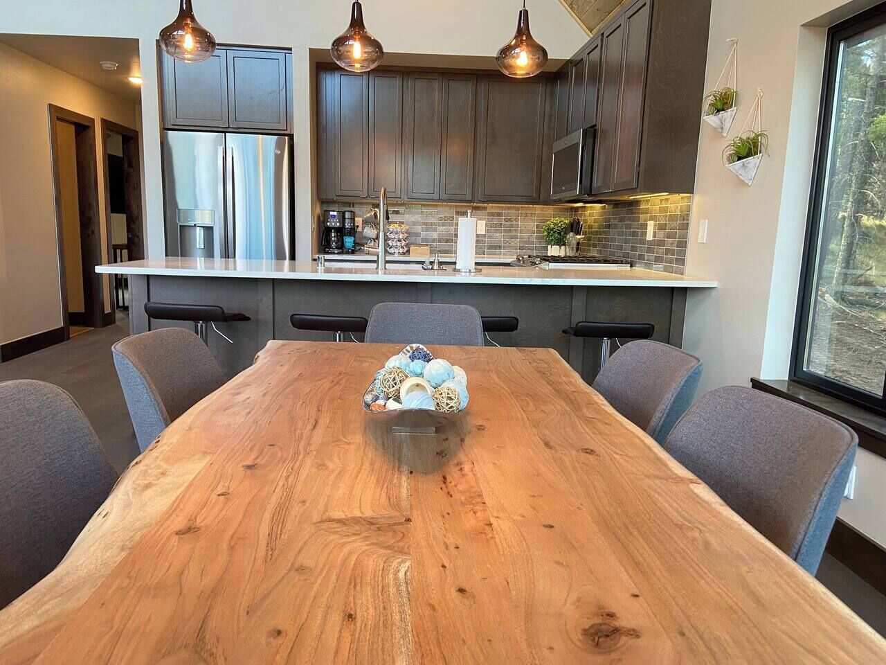 A modern kitchen with dark cabinets, stainless steel appliances, and pendant lighting.