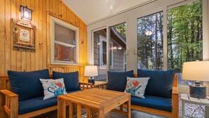 Una habitación acogedora con dos sofás, una mesa de madera y una ventana con vistas al bosque.