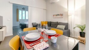 A dining area with a table set for four, a sofa, a lamp, and a potted plant. - Luci A Lago - MyHomeinComo (Como)