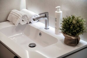 A bathroom sink with a towel, a bottle, and a potted plant. - Luci A Lago - MyHomeinComo (Como)