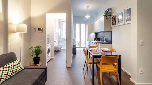 A modern apartment with a dining area, kitchen, and a living room with a sofa and a lamp. - Luci A Lago - MyHomeinComo (Como)