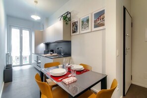 Een moderne keuken met een eettafel gedekt voor twee personen, een klein kookeiland en uitzicht op de stad.