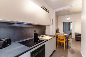 Une cuisine moderne équipée d’une cuisinière intégrée, d’une machine à café et d’un coin repas avec des chaises jaunes.